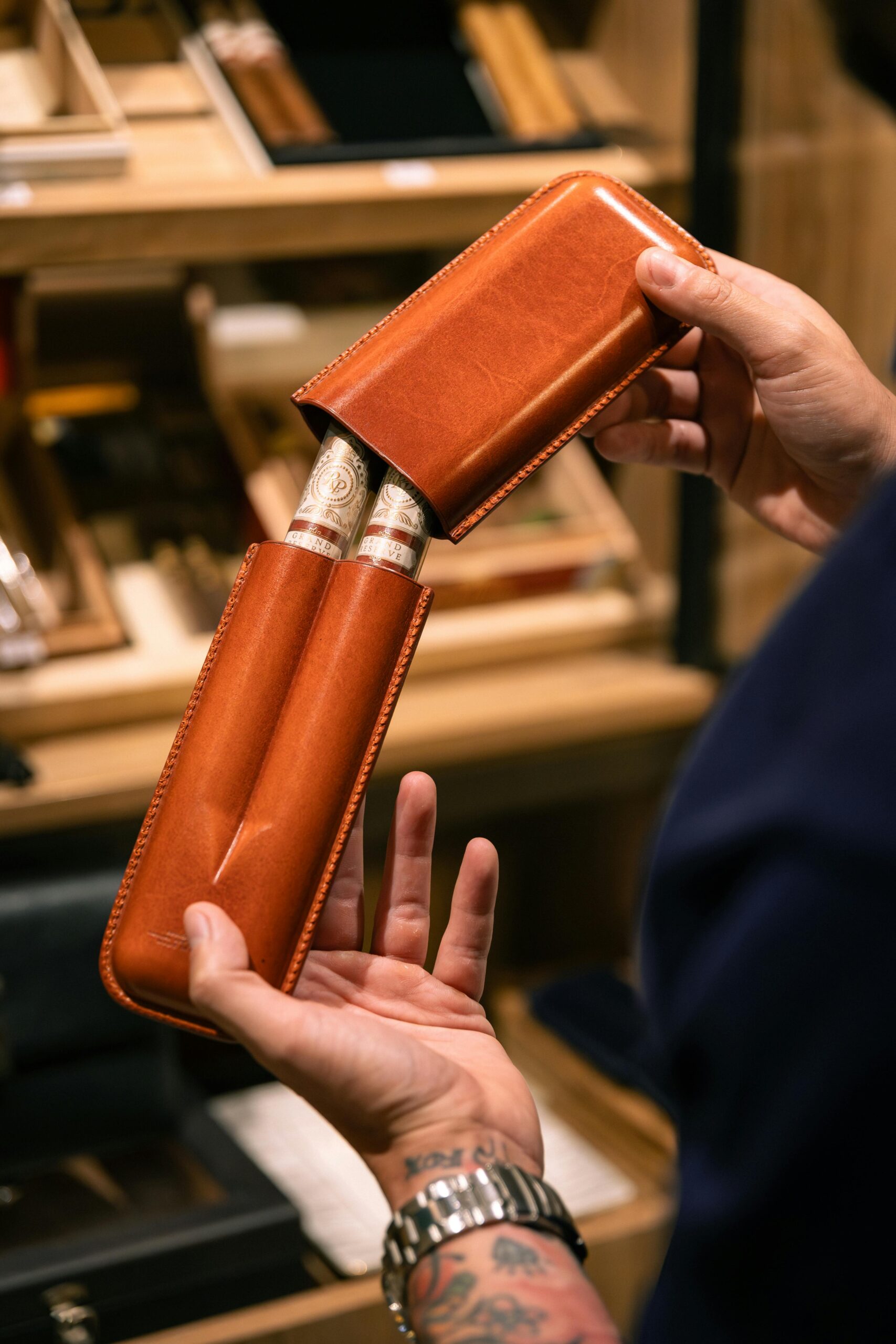 Hands holding premium cigars in a luxury leather case, showcasing elegance and style.